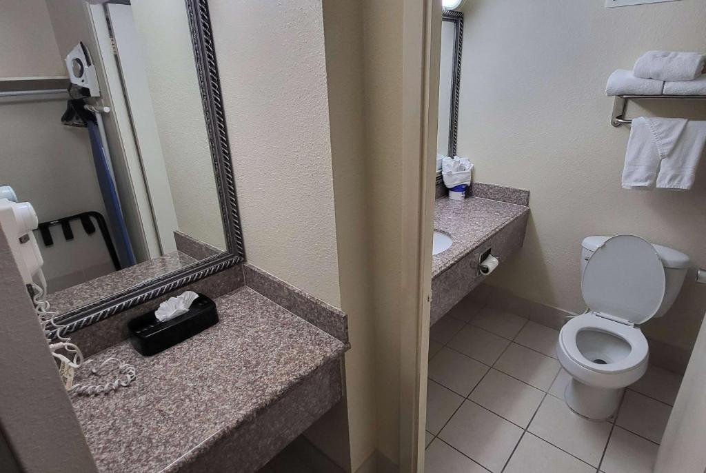 a bathroom with a toilet and a sink and a mirror at Ramada by Wyndham Houston Intercontinental Airport East in Humble