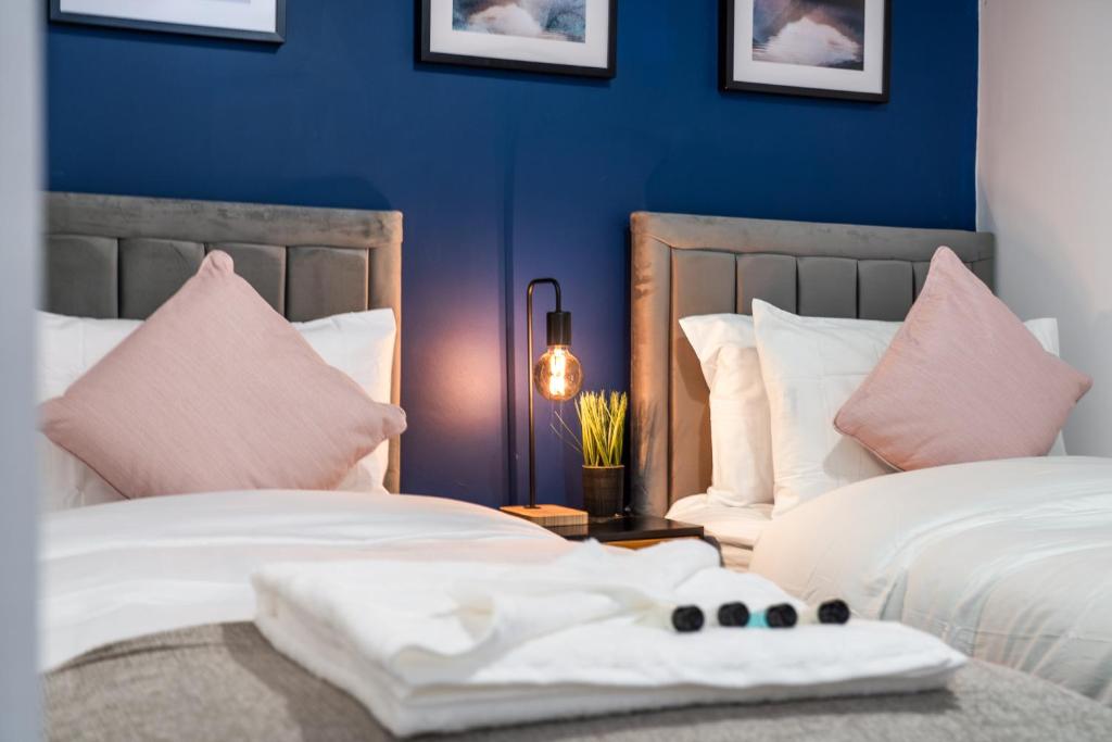 2 camas en una habitación con paredes azules y almohadas rosas en The Hertfordshire Hideaway en Potters Bar