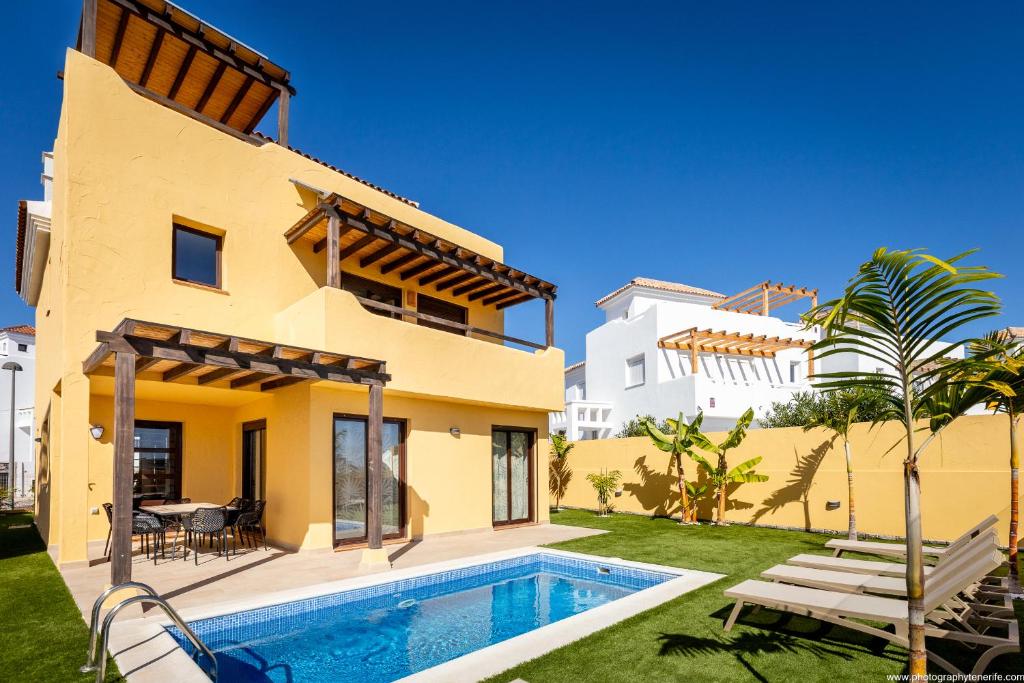 a villa with a swimming pool in front of a house at VILLA WITH 4 BEDROOMS AND PRIVATE HEATED POOL in San Miguel de Abona