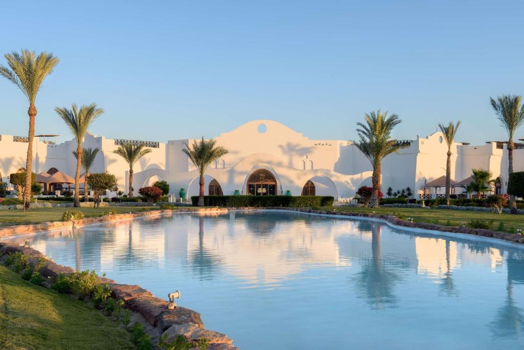 - une piscine en face d'un complexe avec des palmiers dans l'établissement Hilton Marsa Alam Nubian Resort, à Abu Dabab