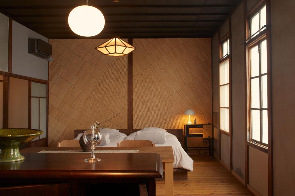 a bedroom with a bed and a table and windows at Lhotel de Mai in Tamba-sasayama