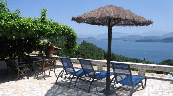 a group of chairs and an umbrella on a patio at Nikatsas Cottage No 1 in (( Kerasá ))