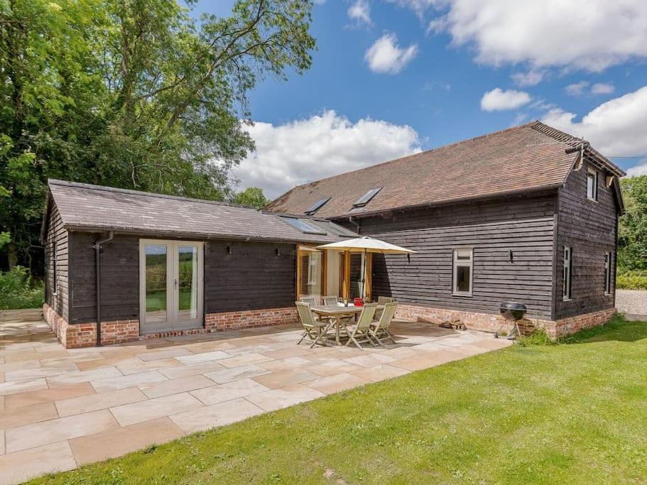 a house with a patio and a table and chairs at Stride’s Barn in Whiteparish