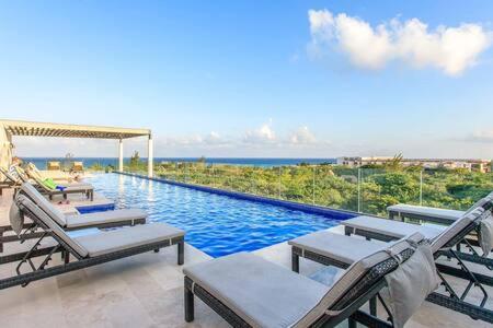 una piscina con tumbonas y el océano en Gorgeous Private Pool with Terrace Steps to Beach and 5th Ave!, en Playa del Carmen