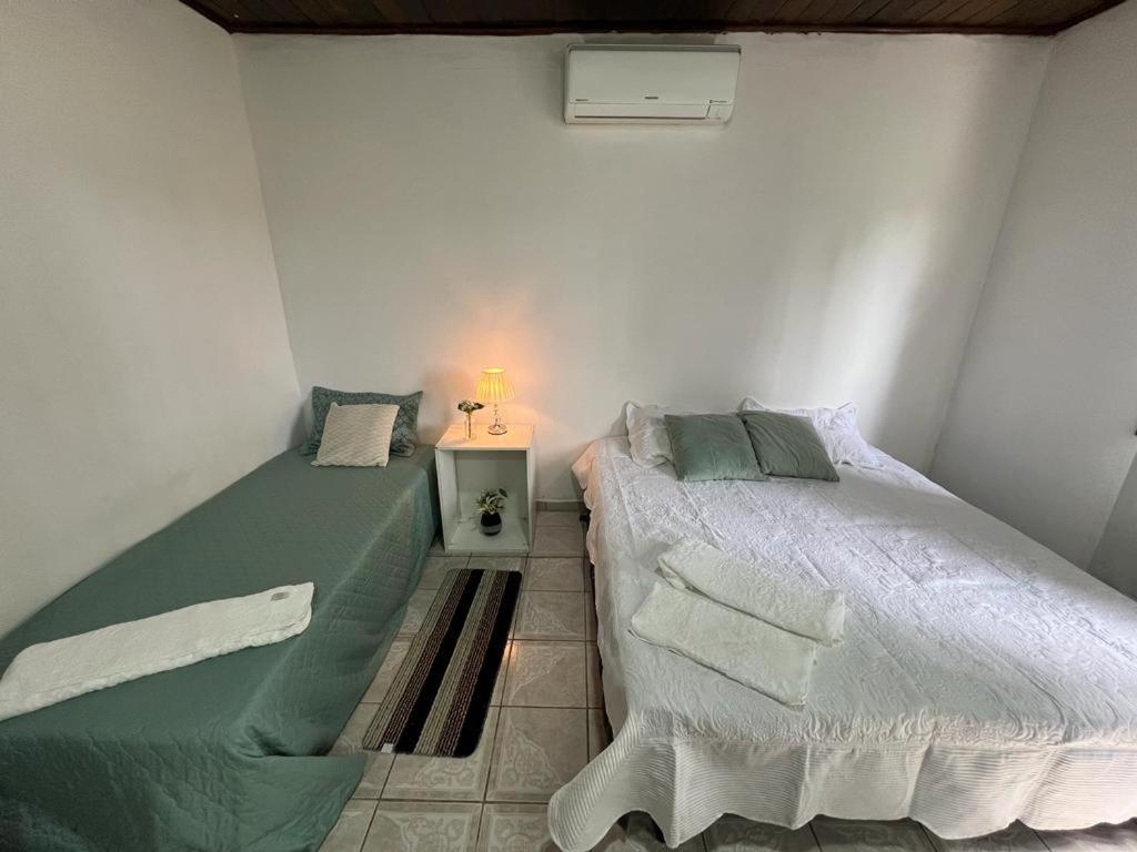 um quarto com 2 camas individuais e uma mesa de cabeceira em Pousada Recanto da Palmeira em Guaíba
