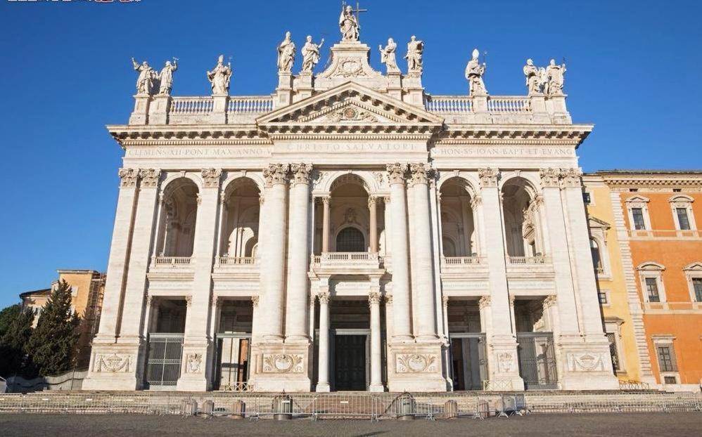un grande edificio bianco con statue sopra di Domus San Giovanni a Roma