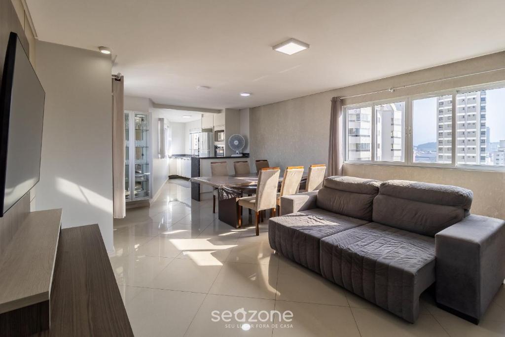 ein Wohnzimmer mit einem Sofa und einem Esstisch in der Unterkunft Apto c/ vaga próx praia e restaurantes BC YVD1301 in Balneário Camboriú