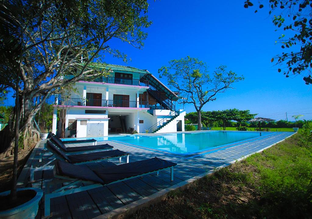 a house with a swimming pool in front of it at Birdsong Leisure Resort in Tissamaharama