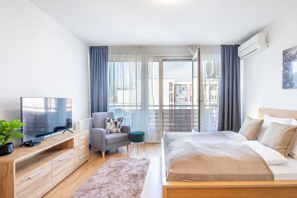 a bedroom with a bed and a tv and a chair at LOTUS Apartments ORIGO with Garage in Budapest