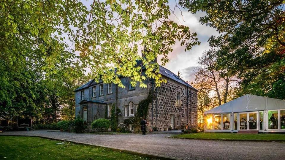 un gran edificio de ladrillo con una tienda delante de él en Durn House, en Portsoy