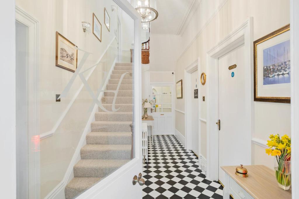 een hal met witte trappen en een zwart-wit geruite vloer bij Kingston House in Torquay