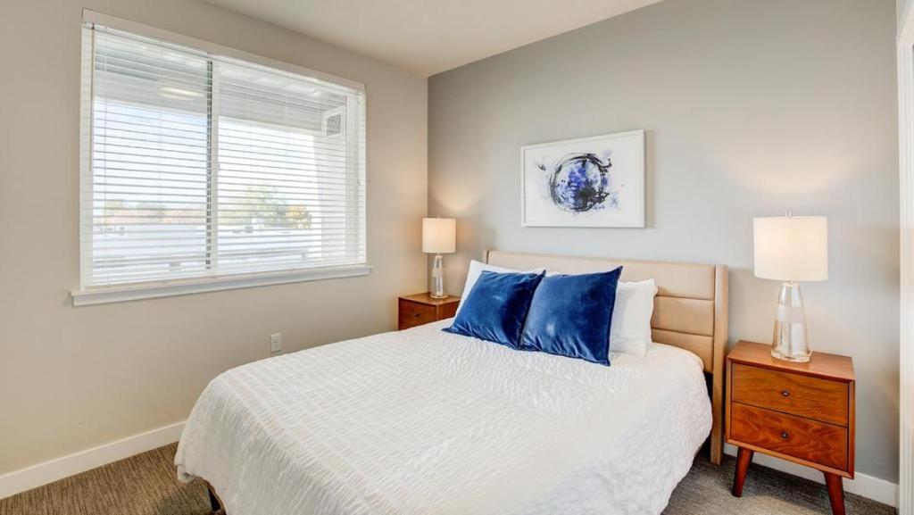 um quarto com uma cama com almofadas azuis e uma janela em Landing Modern Apartment with Amazing Amenities (ID6877) em South Salt Lake