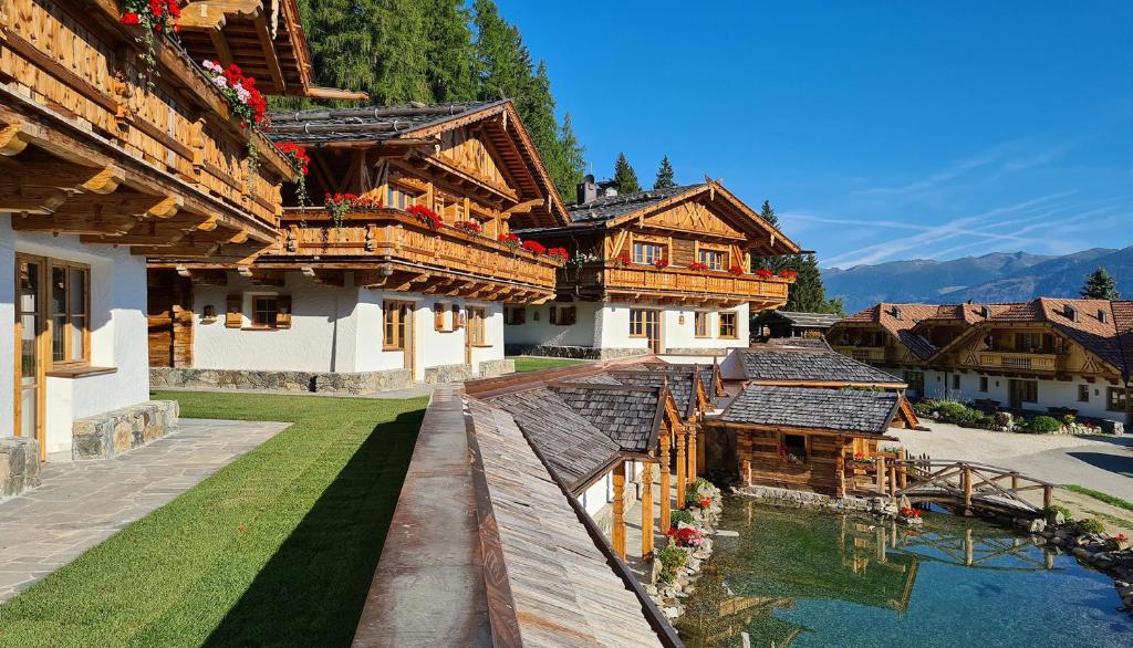 eine Gruppe von Holzgebäuden mit Wasser davor in der Unterkunft Chalets Almdorf Haidenberg in Bruneck