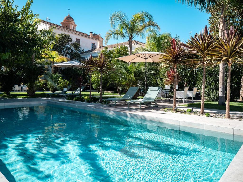 a large swimming pool with chairs and an umbrella at Finca Casabela in Pinos del Valle