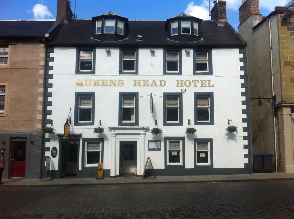 Queenshead Hotel Kelso في كيلسو: مبنى أبيض مكتوب عليه فندق بحجم كوين هيد