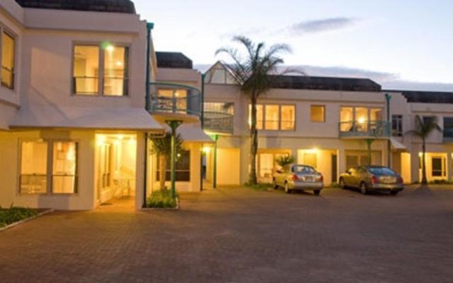 a building with two cars parked in a parking lot at Pacific Harbour Motor Inn in Gisborne