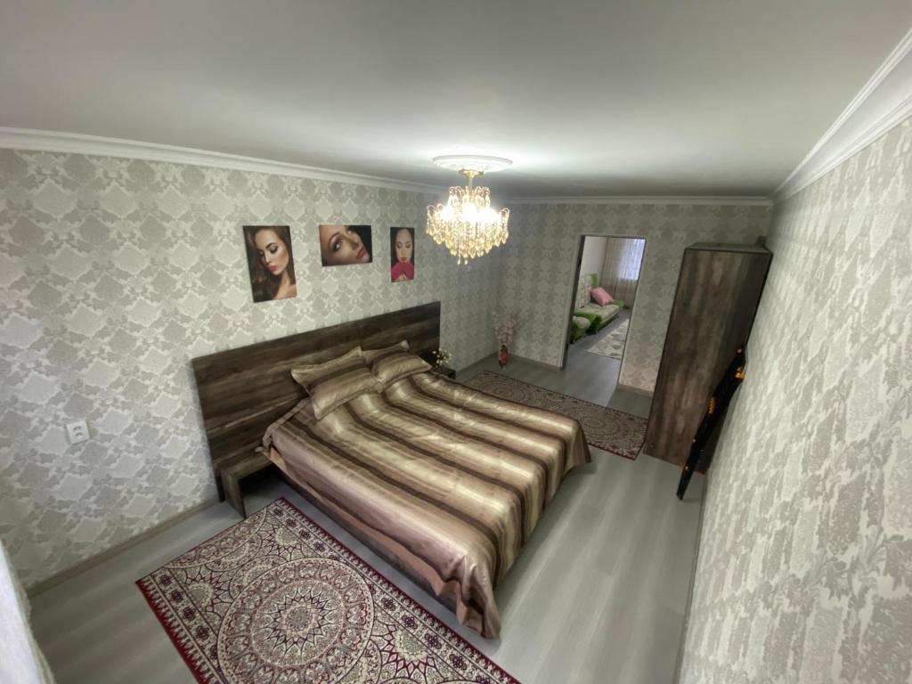 a bedroom with a large bed and a chandelier at Микрорайон Самал дом 38 in Taraz