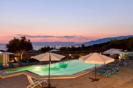 a large swimming pool with umbrellas and chairs at Villa Needa's - New Hope Poolside Studio in Mírton