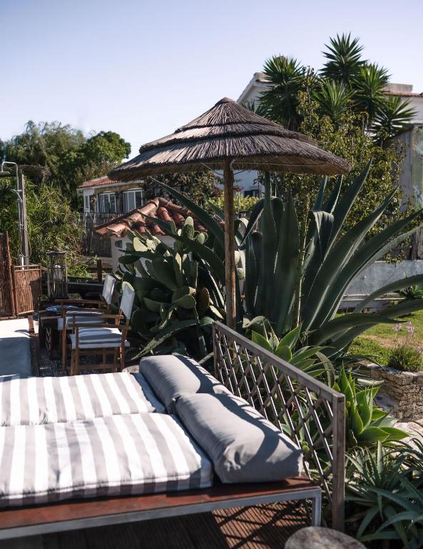 a bench with an umbrella and pillows on it at João Jungle in Açafora