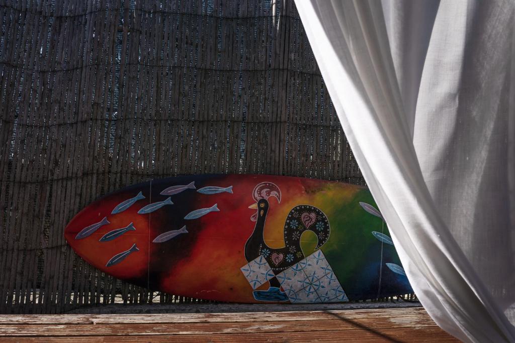 a surfboard with a peacock painted on it next to a curtain at João Jungle in Açafora