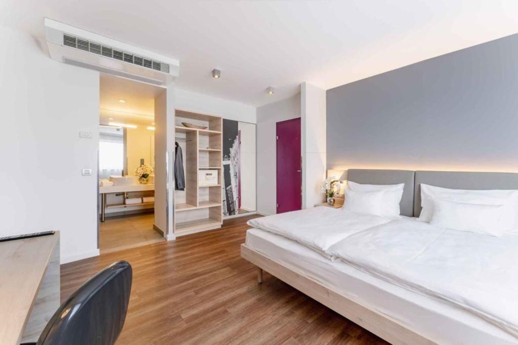 a bedroom with a large white bed and a bathroom at PLAZA INN Wien Gasometer in Vienna