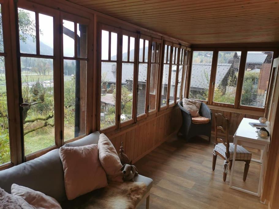 a living room with a couch and a table and windows at Nouveau à Rougemont: Appartement dans Chalet 1830 in Rougemont