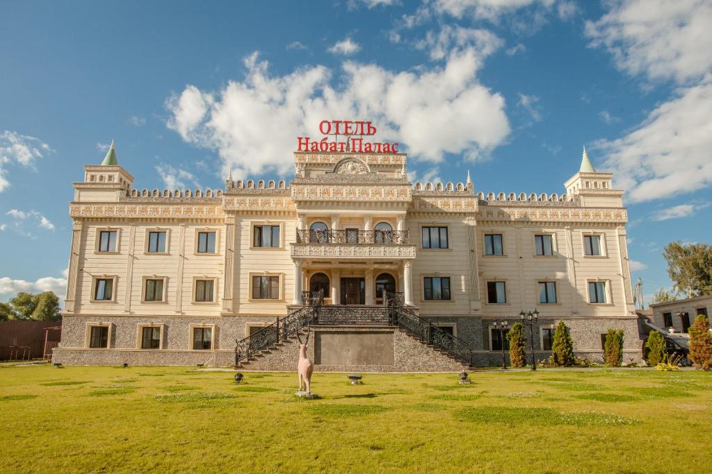 Un grand bâtiment blanc avec un panneau en haut dans l'établissement Nabat Palace Domodedovo, à Voyevodino