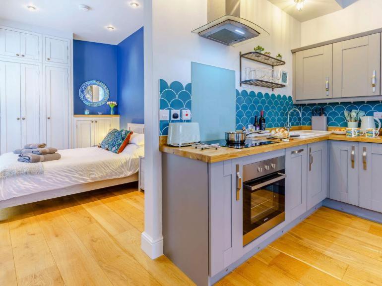 eine Küche mit blauen Wänden und ein Bett in einem Zimmer in der Unterkunft Luxury studio above the stunning Tenby Harbour in Tenby