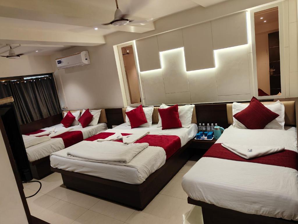 a room with four beds with red and white pillows at Hotel Anand Palace in Shirdi