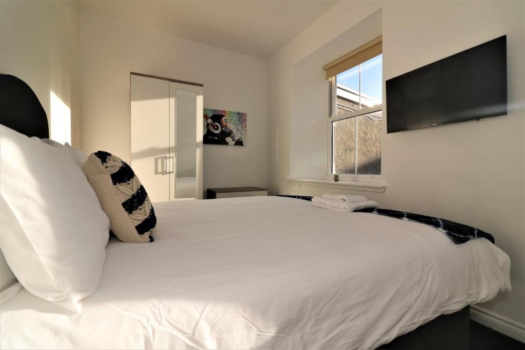 a bedroom with a large white bed and a window at Signature - No 1 Bonnet Apartments in Lanark