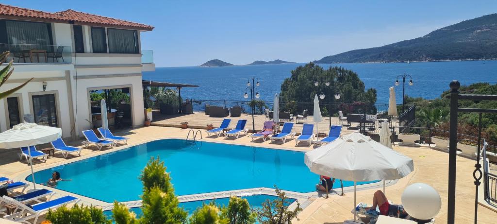a swimming pool with chairs and umbrellas and the water at Grand süit 402 in Kalkan