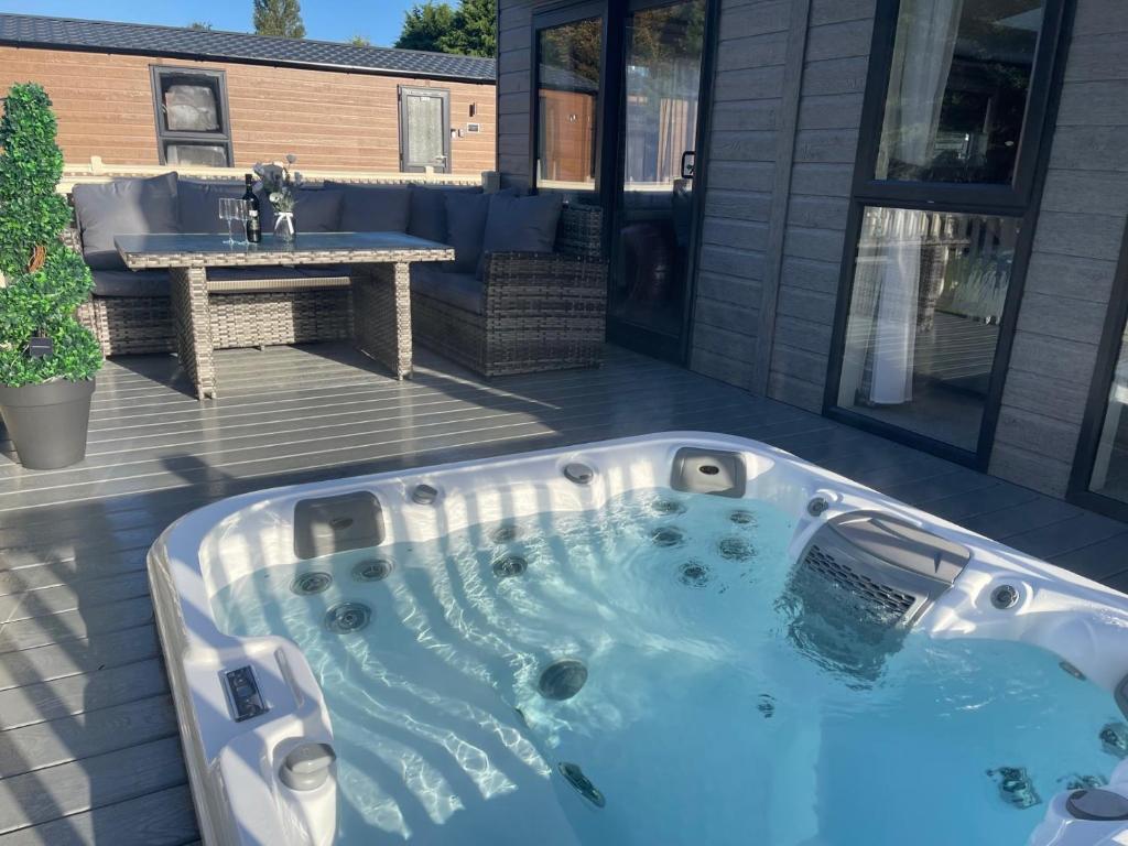 a jacuzzi tub on a patio with a table at Ailsa Lodge with Hot Tub in York