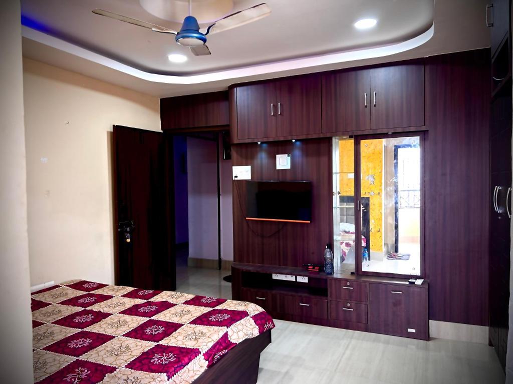 - une chambre avec un lit, des placards en bois et une télévision dans l'établissement Angel guest house, à Guwahati