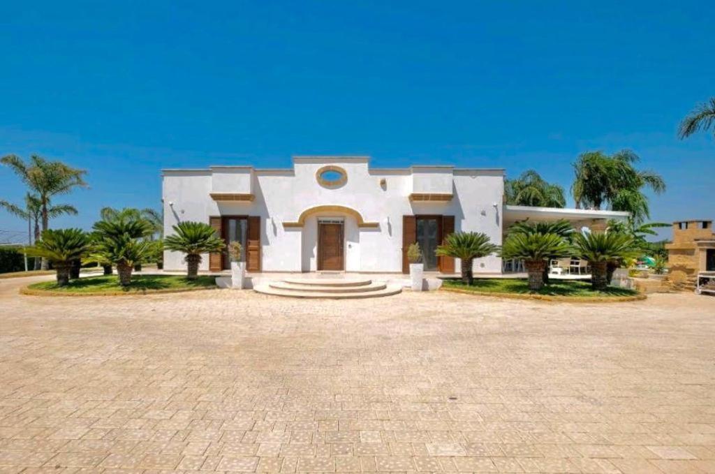 Una gran casa blanca con palmeras delante. en Villa Perla Salentina luxury, en Taviano
