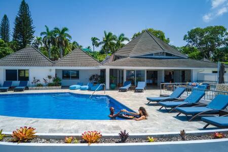 a little girl laying in the sand near a swimming pool at Hospitality Expert Eden 7BR Pools Beach in Montego Bay
