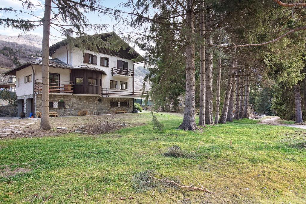 a large house in the middle of a field with trees at Maison La Truite in Morgex