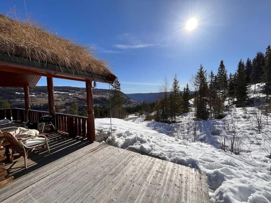 a snow covered porch of a cabin with a thatched roof at Ål Skisenter - Cabin with panoramic view for 8 guests in Holo