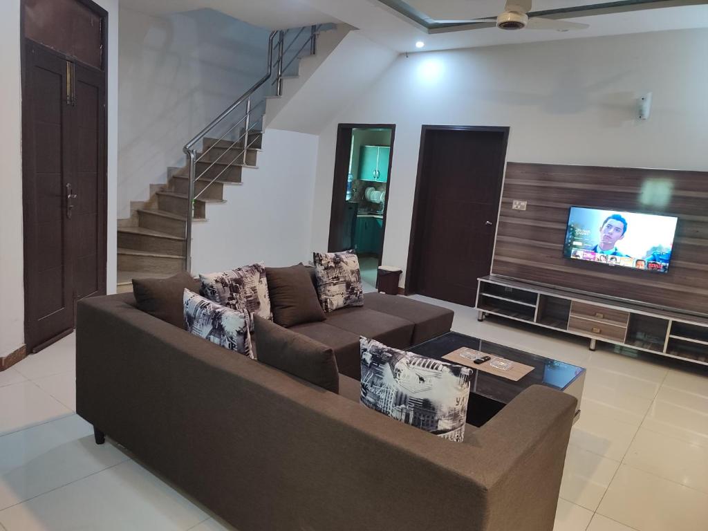 Il comprend un salon doté d'un canapé et d'une télévision à écran plat. dans l'établissement 2 BR Serviced Holiday Home Near Lahore Ring Road, à Lahore