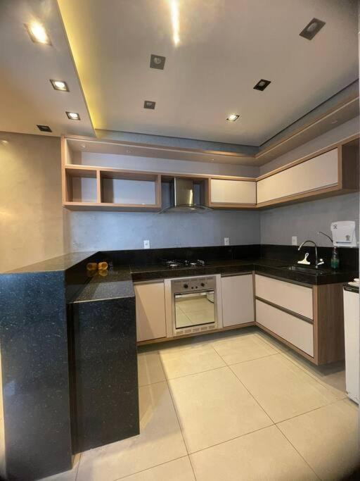 a kitchen with a black counter top and an oven at apartamento alto padrão (centro) in Ubá