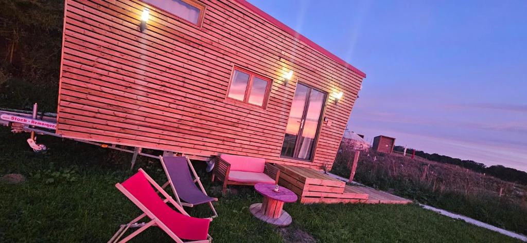 une petite maison avec des chaises roses et violettes dans la cour dans l'établissement Tiny house cosy proche Disney, à Bannost