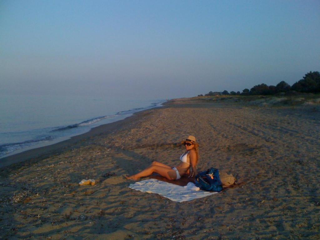 uma mulher sentada numa toalha na praia em maison T3 500m de la plage em Poggio-Mezzana