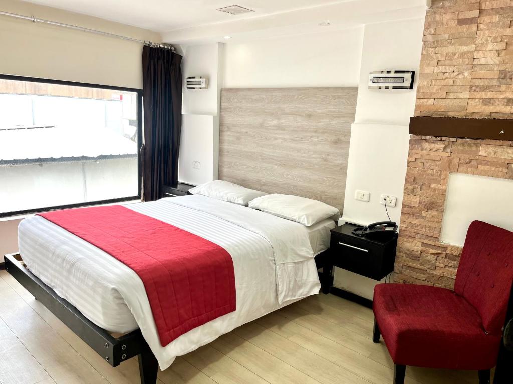 1 dormitorio con 1 cama grande y 1 silla roja en Hotel Imperial, en Ambato