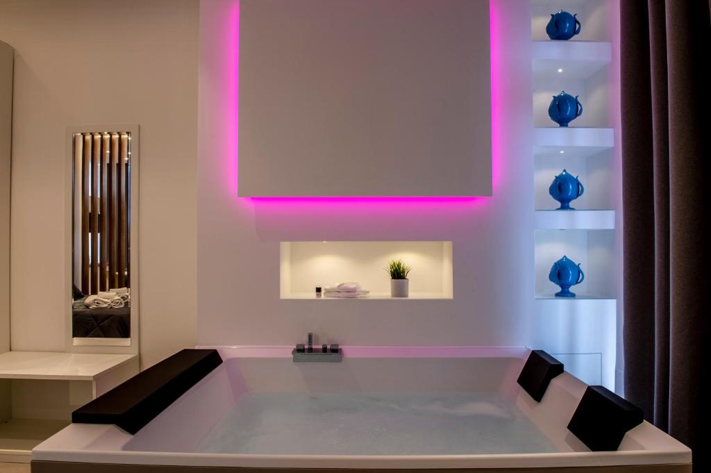 una vasca da bagno bianca con illuminazione rosa di Alipa Suite with Jacuzzi a Monopoli