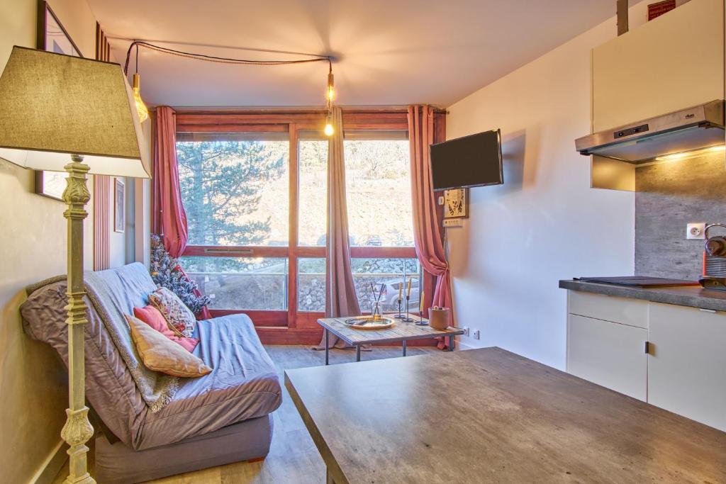 a living room with a couch and a window at Studio pied des pistes - Villard in Villard-de-Lans
