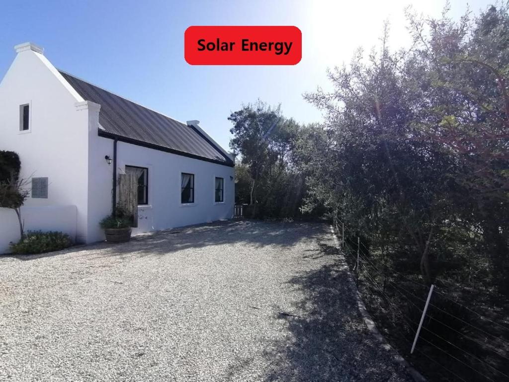 una casa blanca con un cartel que lee energía solar en Matjesfontein Estate Keurbooms Chalet, en Plettenberg Bay