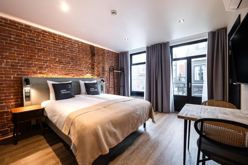 a bedroom with a large bed and a brick wall at limehome Amsterdam Leidsekruisstraat in Amsterdam