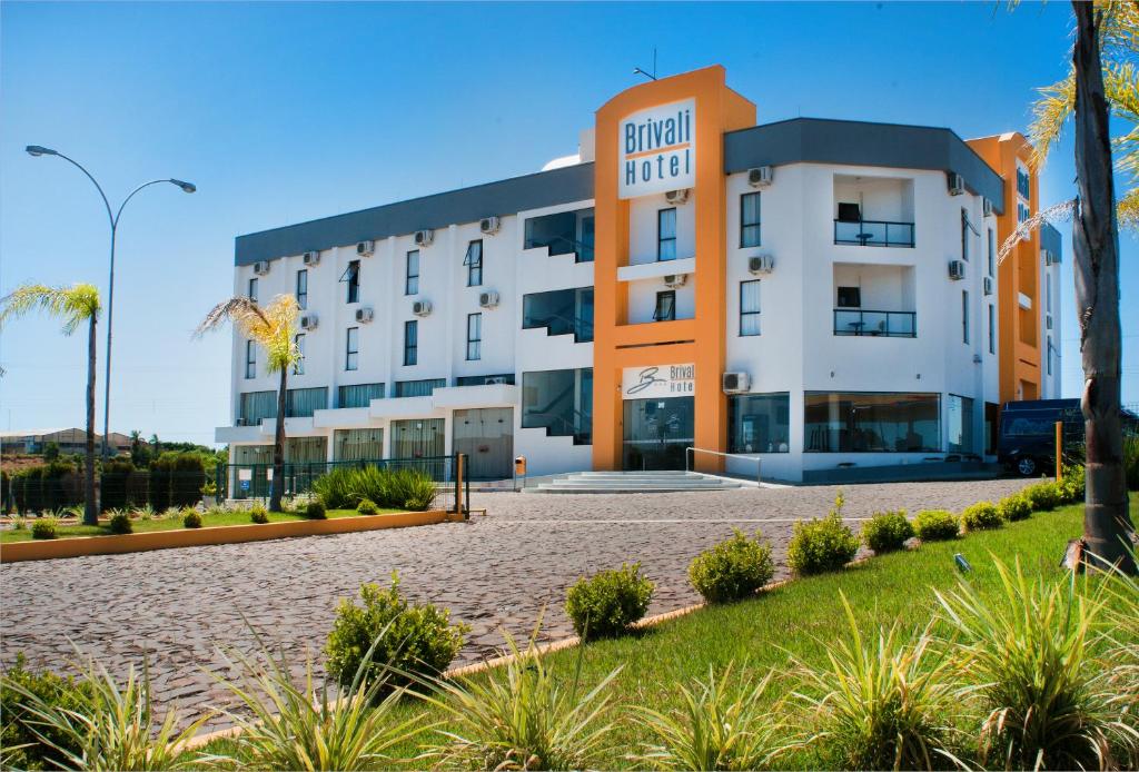 a hotel building with palm trees in front of it at Brivali Hotel e Eventos in Caçador