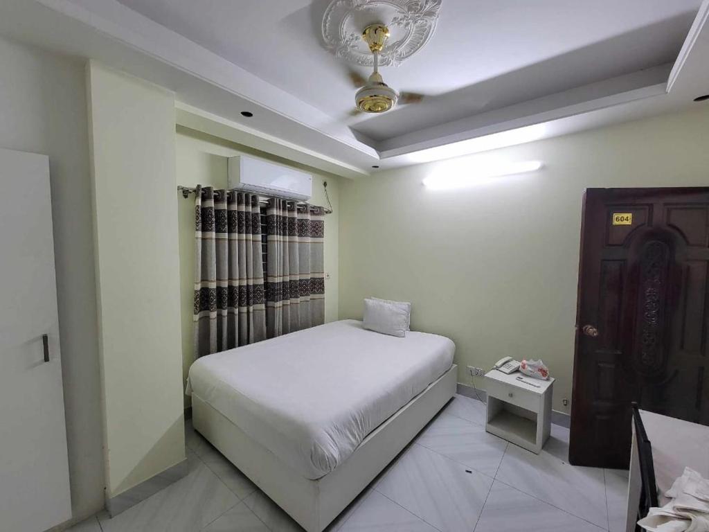1 dormitorio con cama blanca y techo en Hotel White Stone en Dhaka