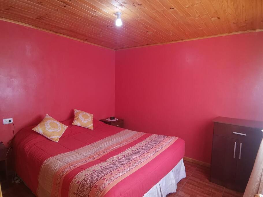 a red bedroom with a bed and a wooden ceiling at Cabaña El Quillay in Linares