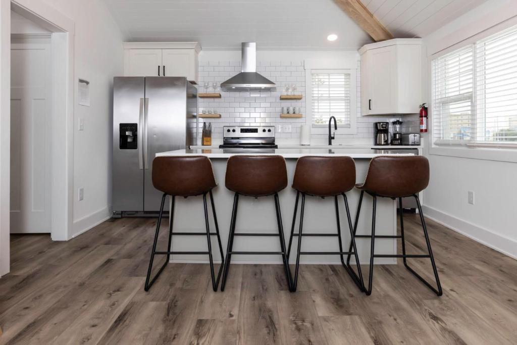 a kitchen with a counter with stools and a refrigerator at Ocean Lofts in the Vibe #4 - 5 min walk to beach in Virginia Beach